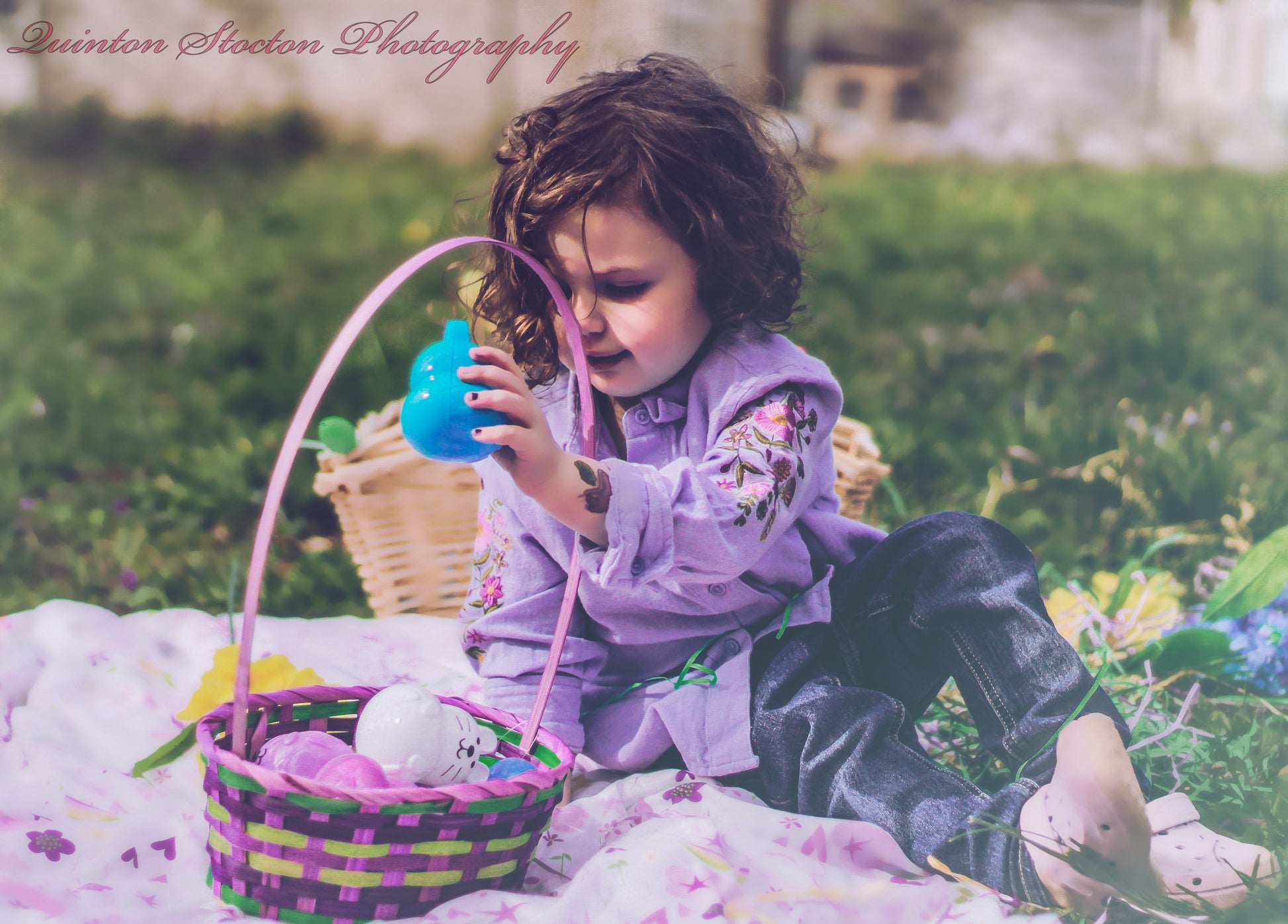 Little girl enjoying Easter egg hunt during event photography session, holding blue egg.