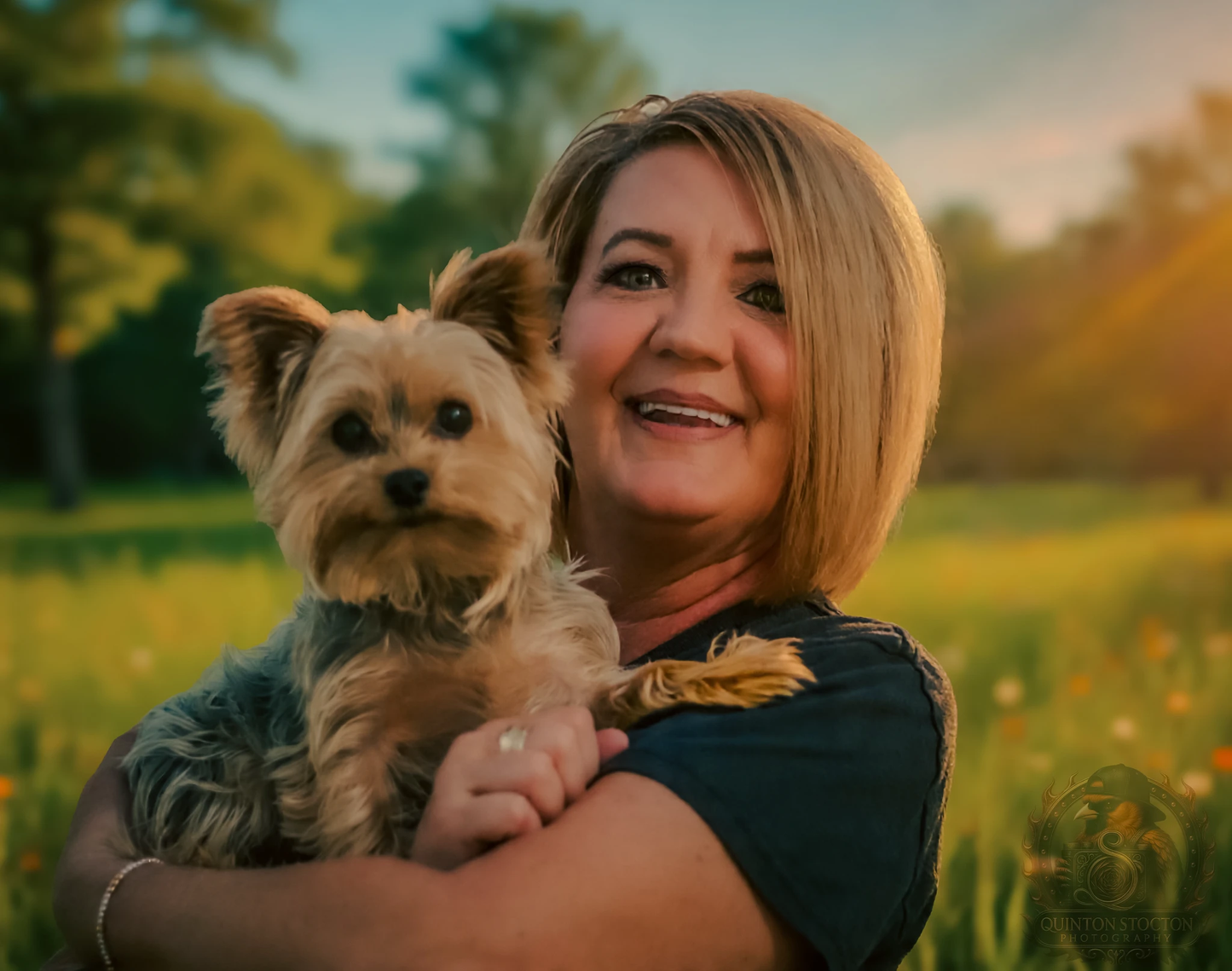 Woman holding a small dog in a field with a blurred background