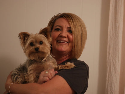 Woman holding a small dog against a plain background