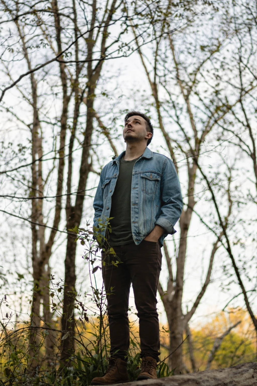 Man in denim jacket standing in forest outdoors, Quinton Stocton Photography style