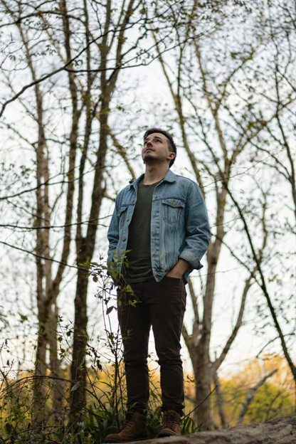 Man in denim jacket standing in forest outdoors, Quinton Stocton Photography style