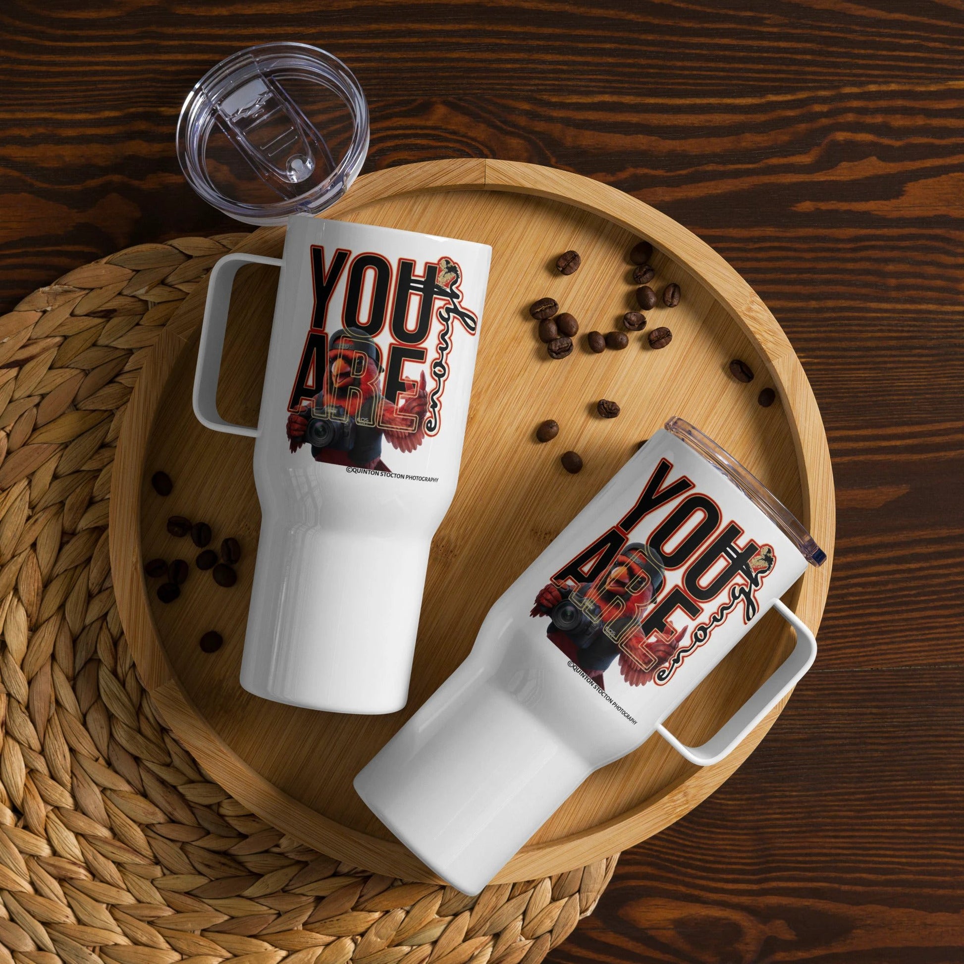 Two white stainless-steel insulated mugs with YOU ARE ENOUGH design on a wooden tray, coffee beans, and clear lid.