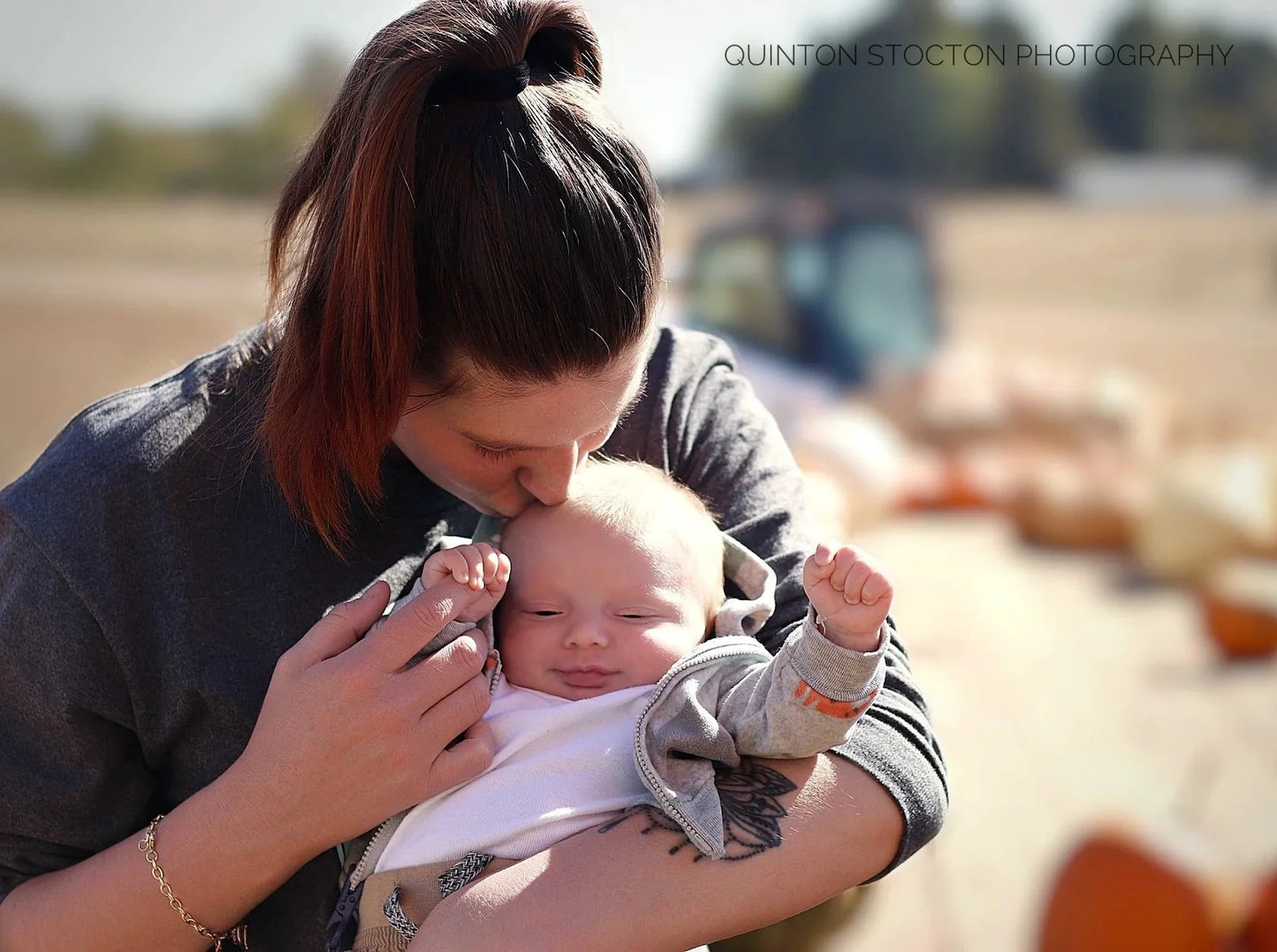Quinton Stocton Photography: mother kisses baby outdoors, Kentucky event coverage with versatile services.