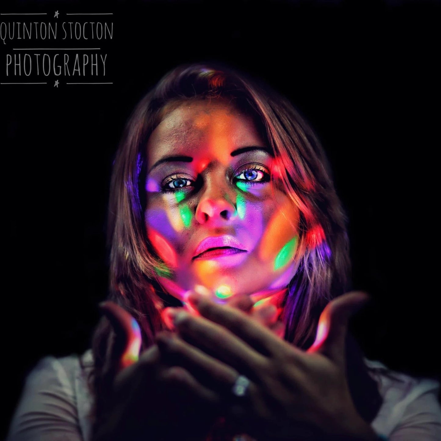 Woman with colorful light effects on a dark background, credited to Quinton Stocton Photography.